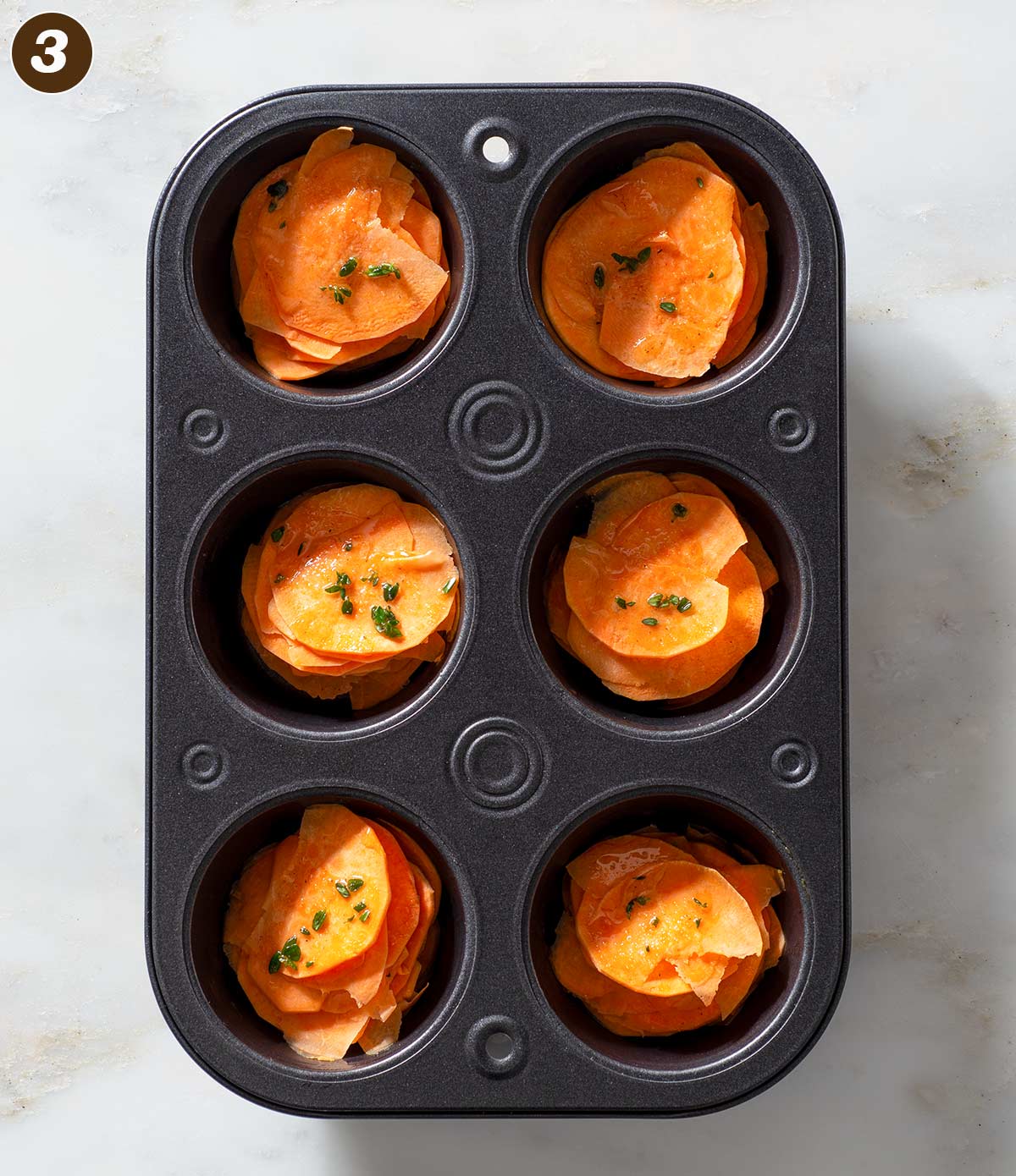 Unbaked sweet potato stacks in a muffin pan.