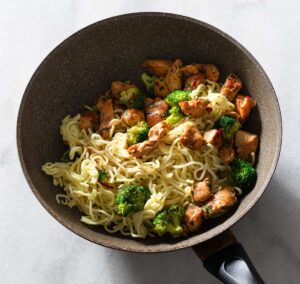 Chicken, broccoli and hokkien noodles in a pan.