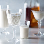 Bourbon milk punch in glasses and a bottle of Bourbon.