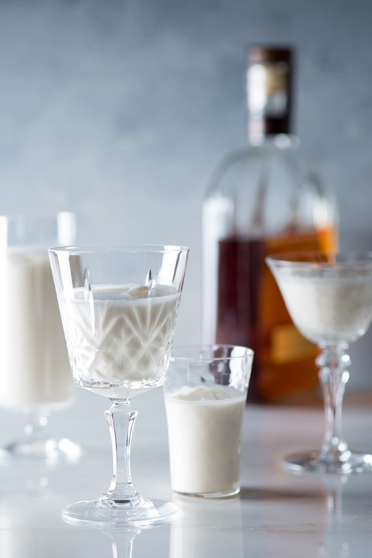 Bourbon milk punch in glasses and a bottle of Bourbon.