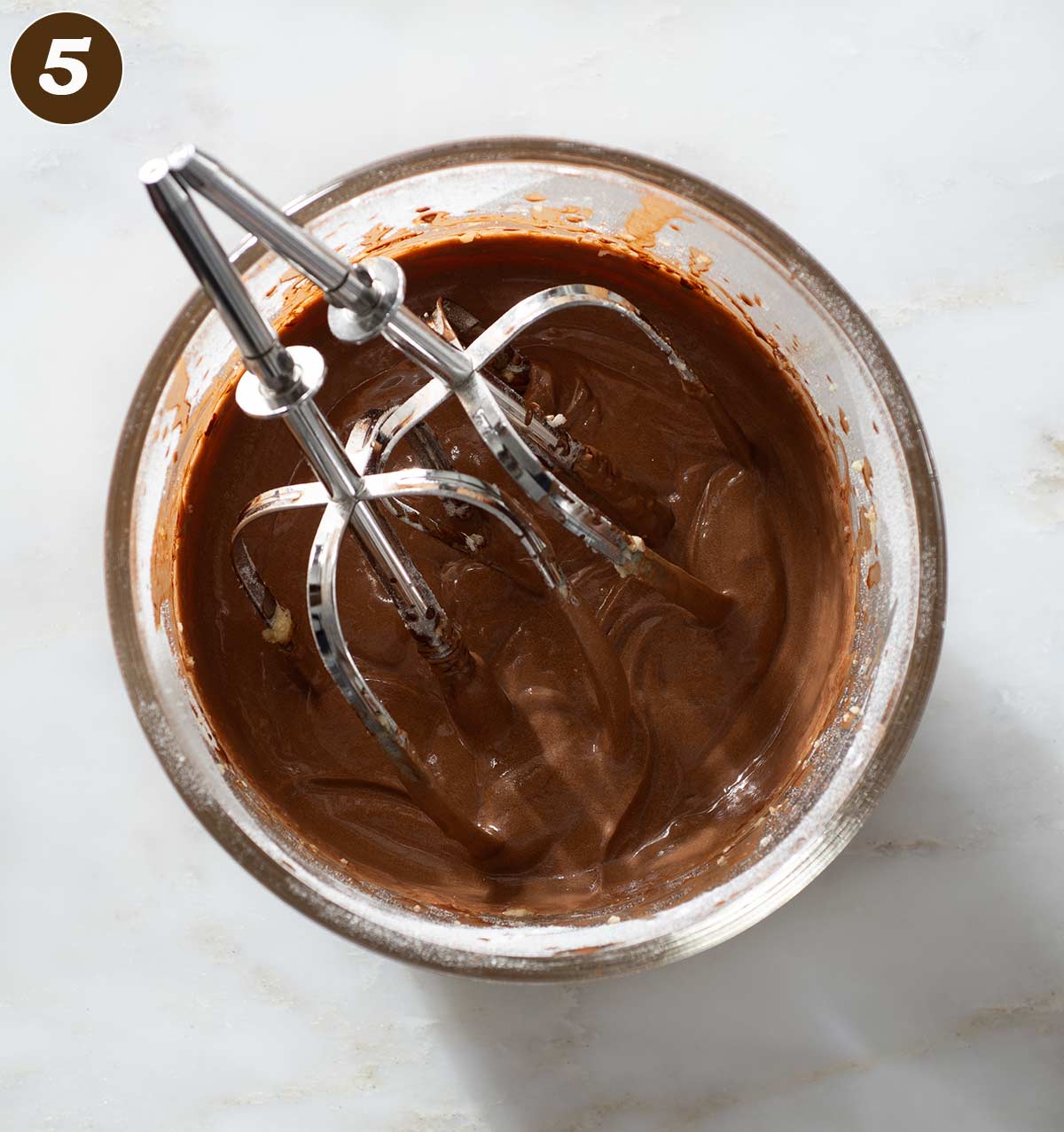 Chocolate batter in a bowl with beaters.