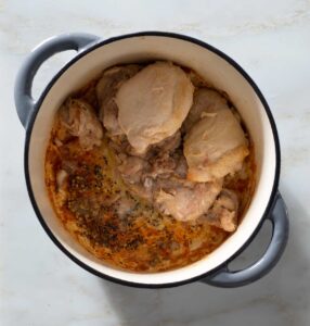 Seared chicken thighs and spice seeds in a Dutch oven.