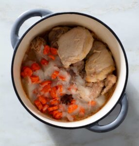 Chicken, spice seeds and vegetables in a Dutch oven.