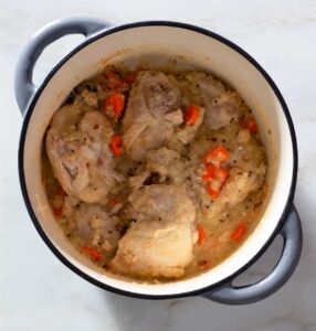 Chicken, spice seeds and cooked vegetables in a Dutch oven.