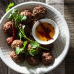 Cilantro meatballs with dipping oil on a plate.