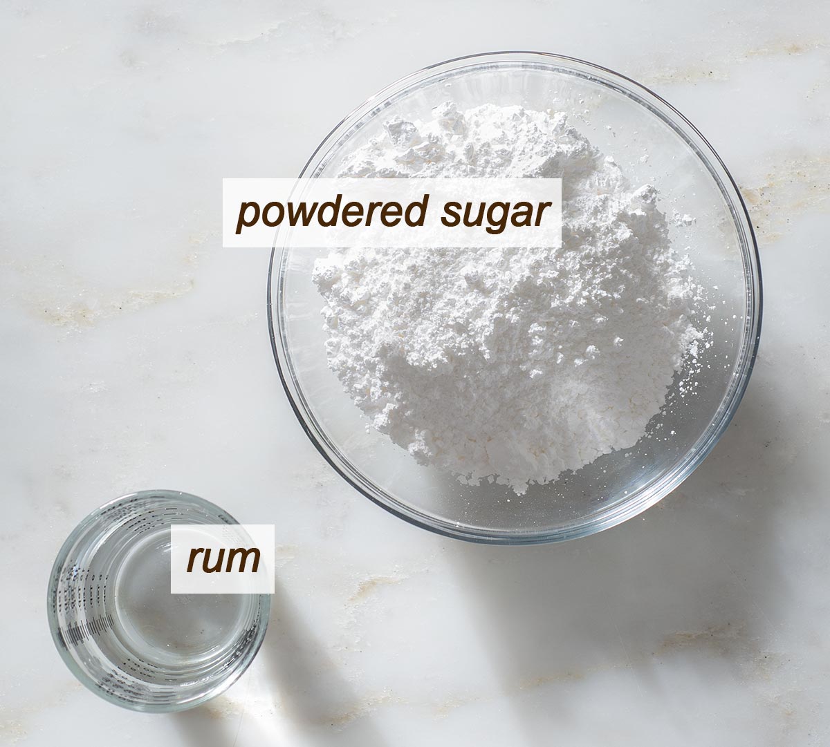 Powdered sugar and rum in bowls on a table.
