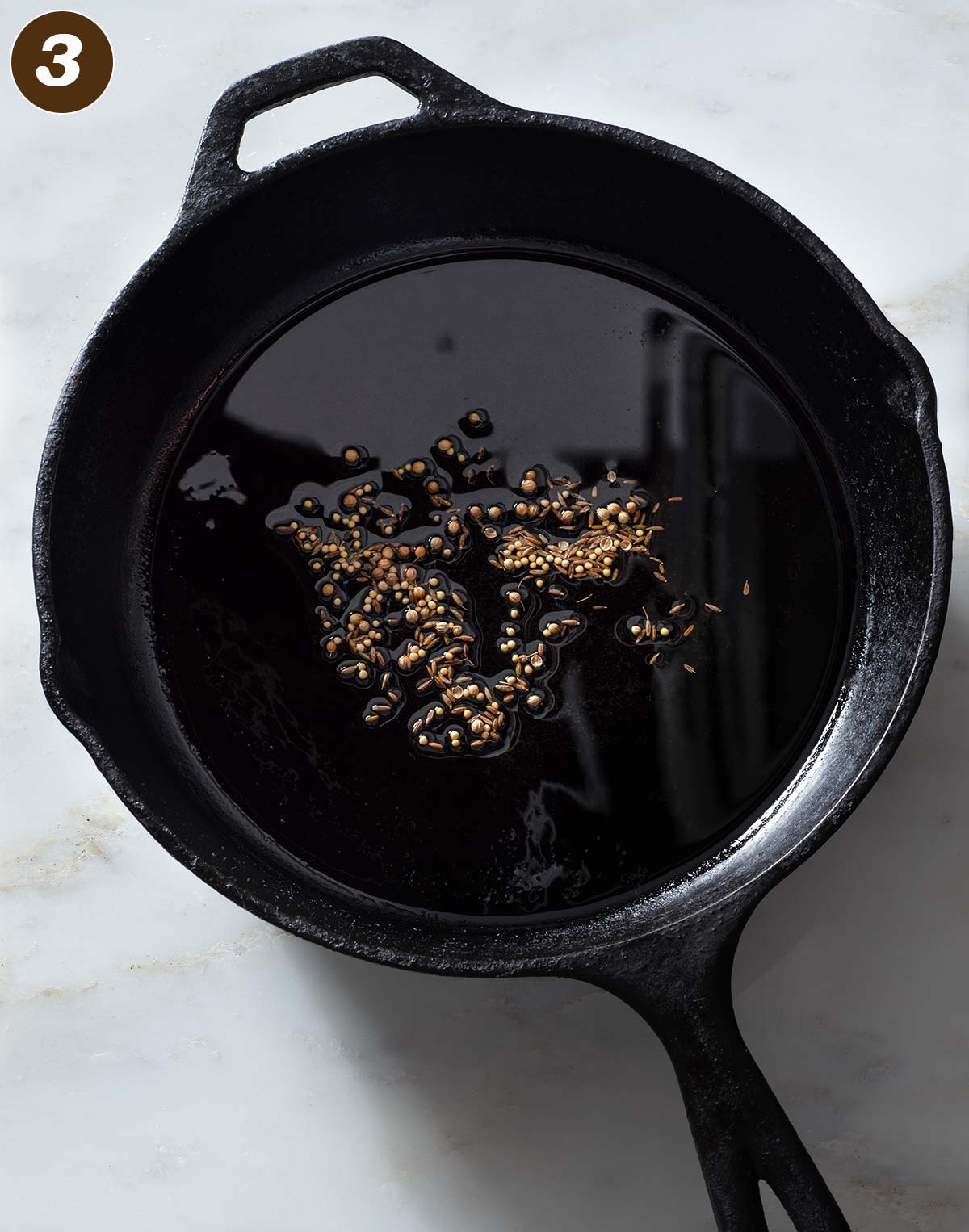 Spice seeds and oil in a cast iron pan.