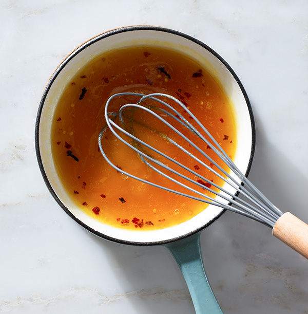 Maple orange glaze being whisked in a saucepan.