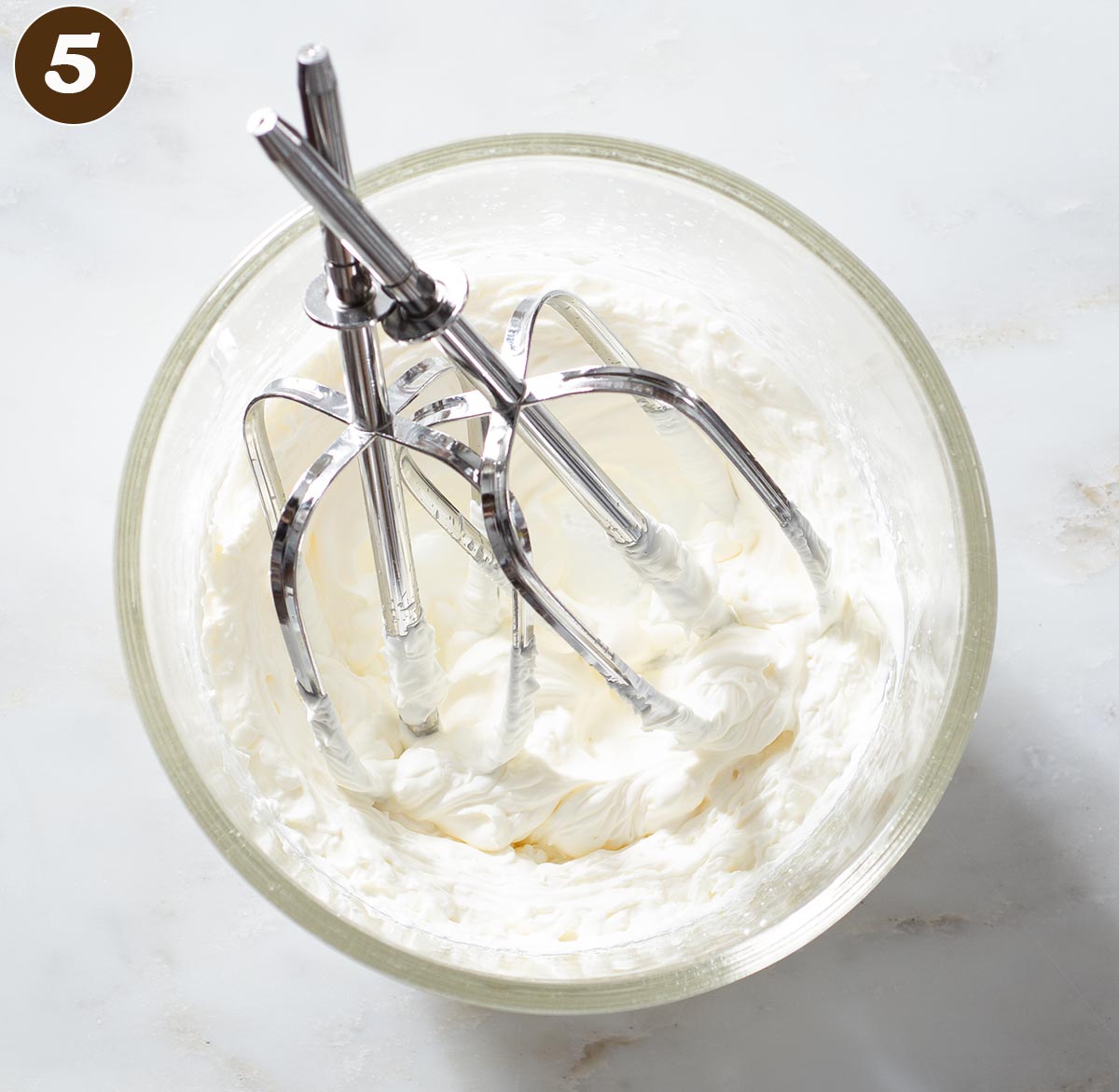 Whipped cream in a bowl with beaters.