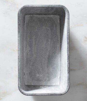 A greased and floured loaf pan on a table.