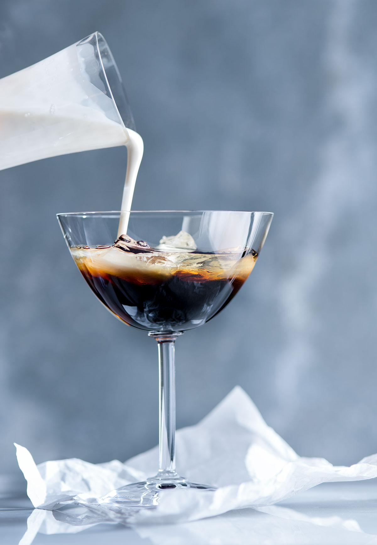White Russian cocktail being poured into a glass.
