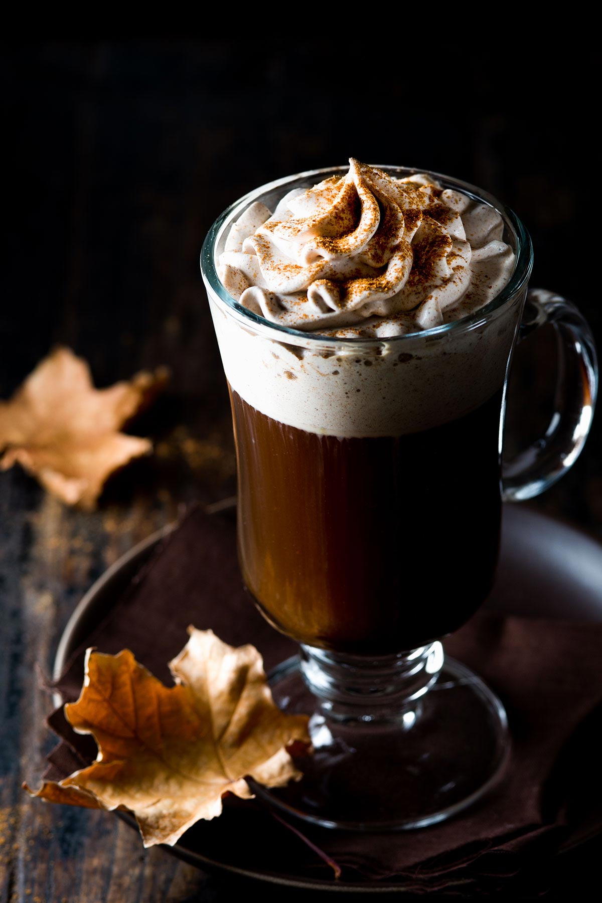 Spiced Irish coffee in a glass with fall leaves.
