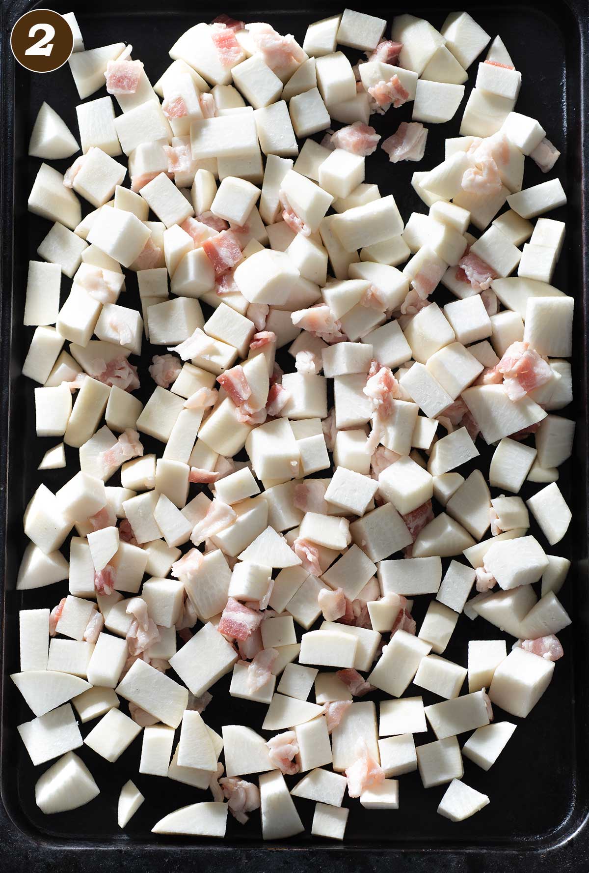 Diced turnip and bacon on a baking sheet.