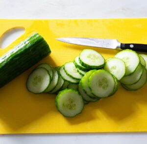 Sliced cucumber on a cutting mat.