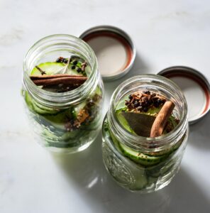 Sliced cucumber and spices in canning jars.