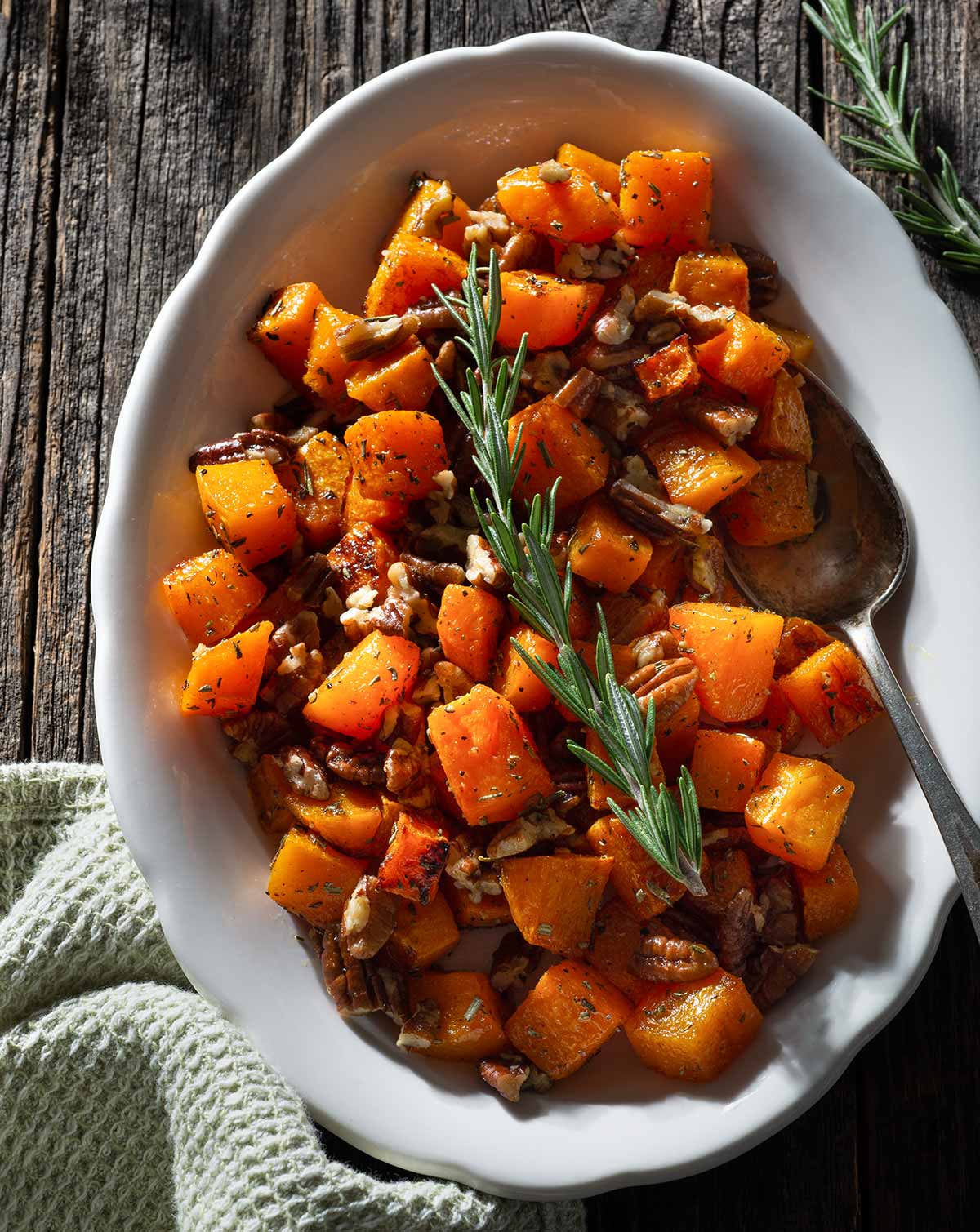 Roasted butternut squash with pecans and rosemary on a plate.
