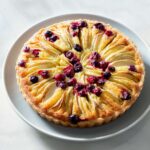 An apple cranberry frangipane tart on a plate.