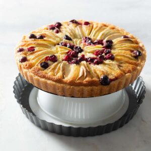 A baked apple cranberry tart on an upside down bowl.