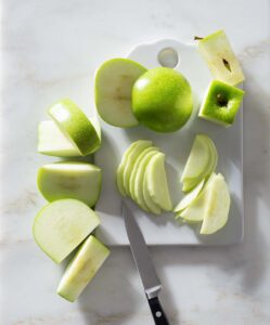 Sliced apples and a knife on a cutting board.