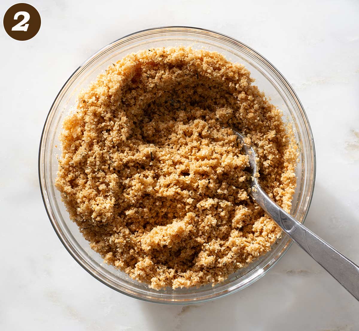 Crushed graham crackers being stirred in a bowl.