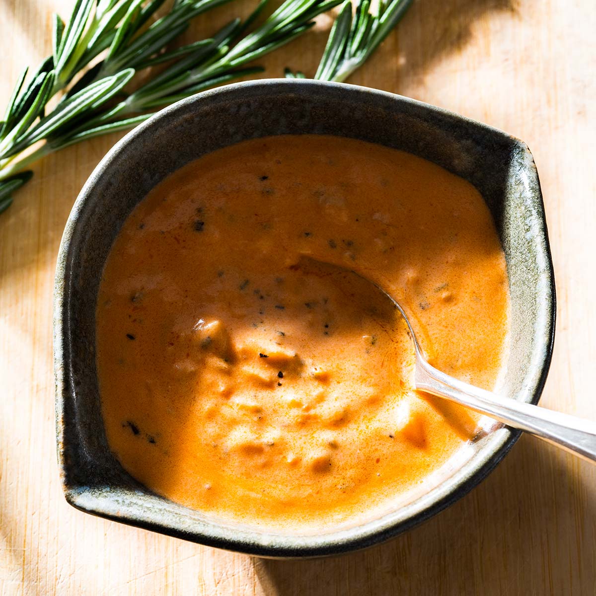 Rosemary cream sauce in a bowl with a spoon.