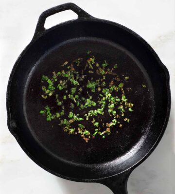 Charred scallions in a cast iron skillet.