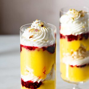 Two individual raspberry lemon curd trifles in tall glasses.