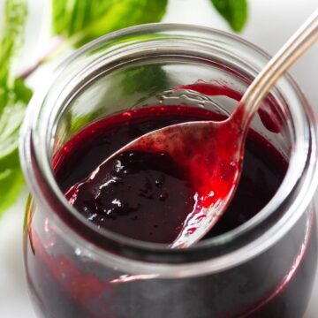 Blackberry sauce in a jar with a spoon.