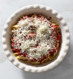 Stuffed shells with sauce and cheese in a baking dish.
