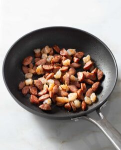 Browned shrimp and sausage in a nonstick pan.