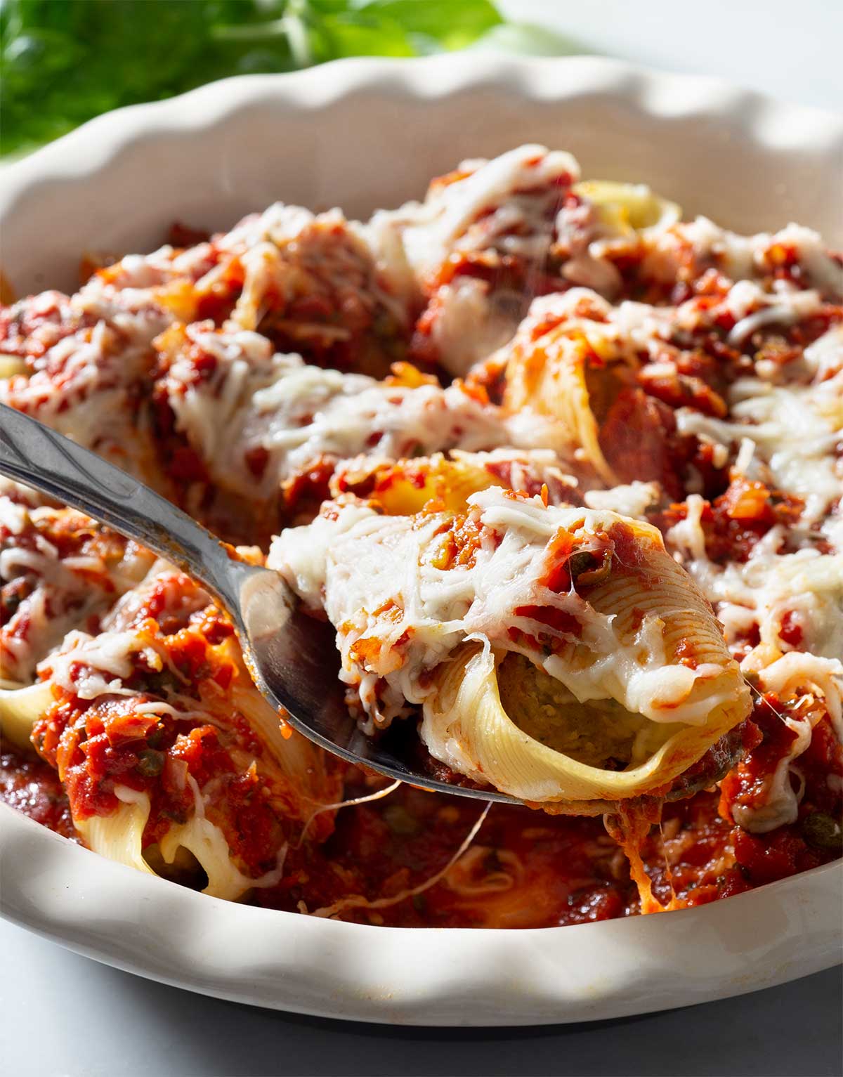 Meatball-stuffed pasta shells with tomato sauce in a round baking dish.