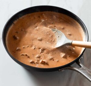 Jerk shrimp pasta sauce being stirred in a pan.