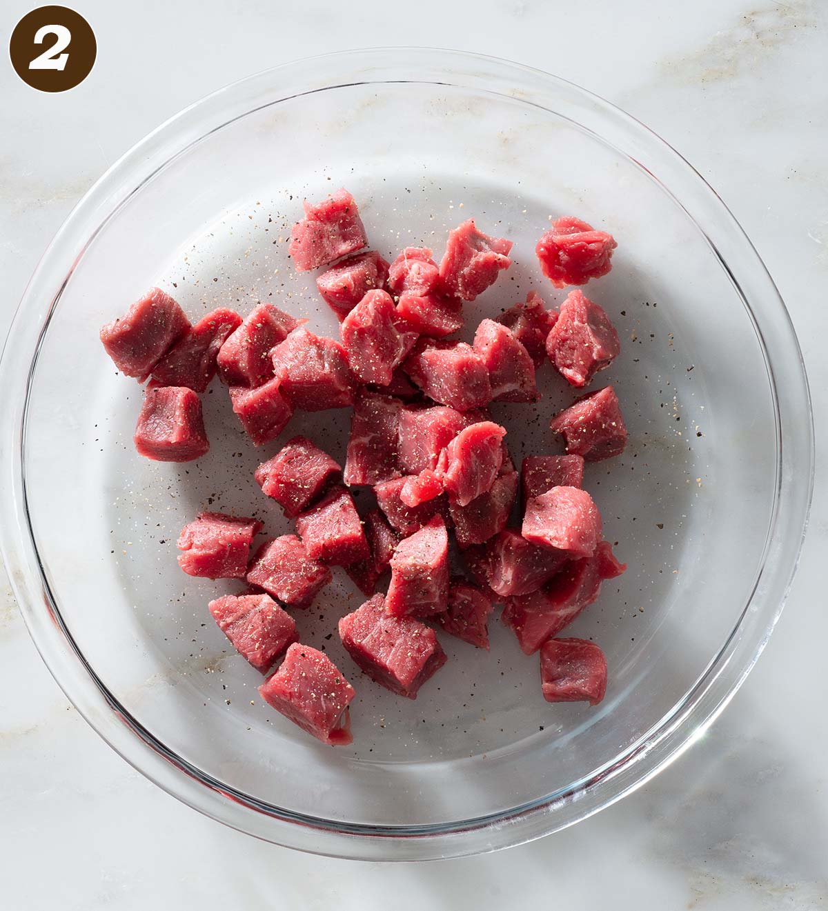 Raw beef chunks on a glass plate.
