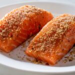 Two spice-rubbed salmon fillets on a white plate.