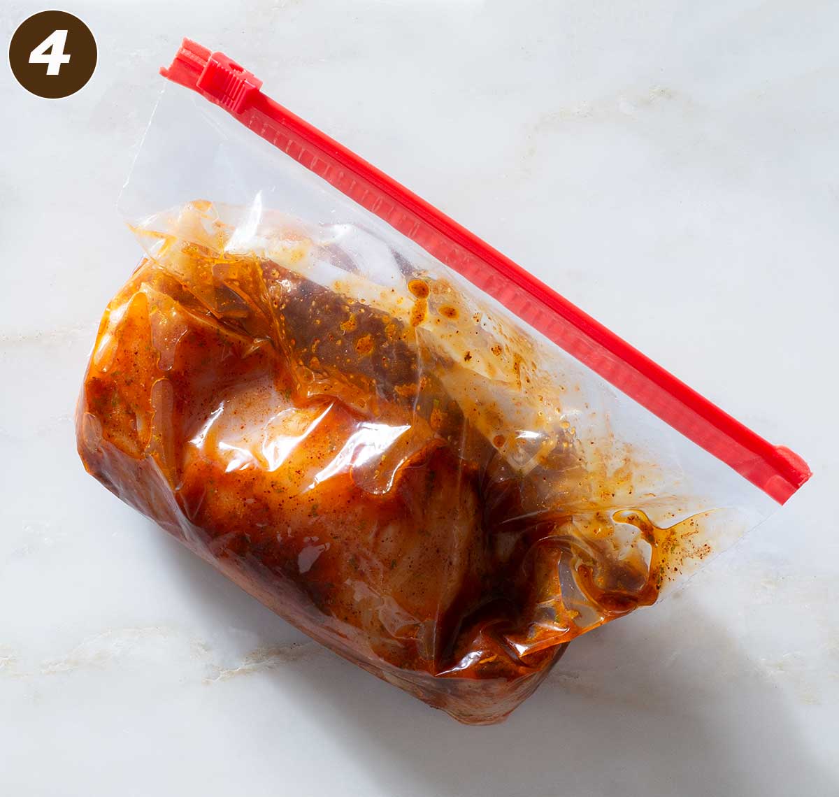 Chicken with marinade in a plastic bag.