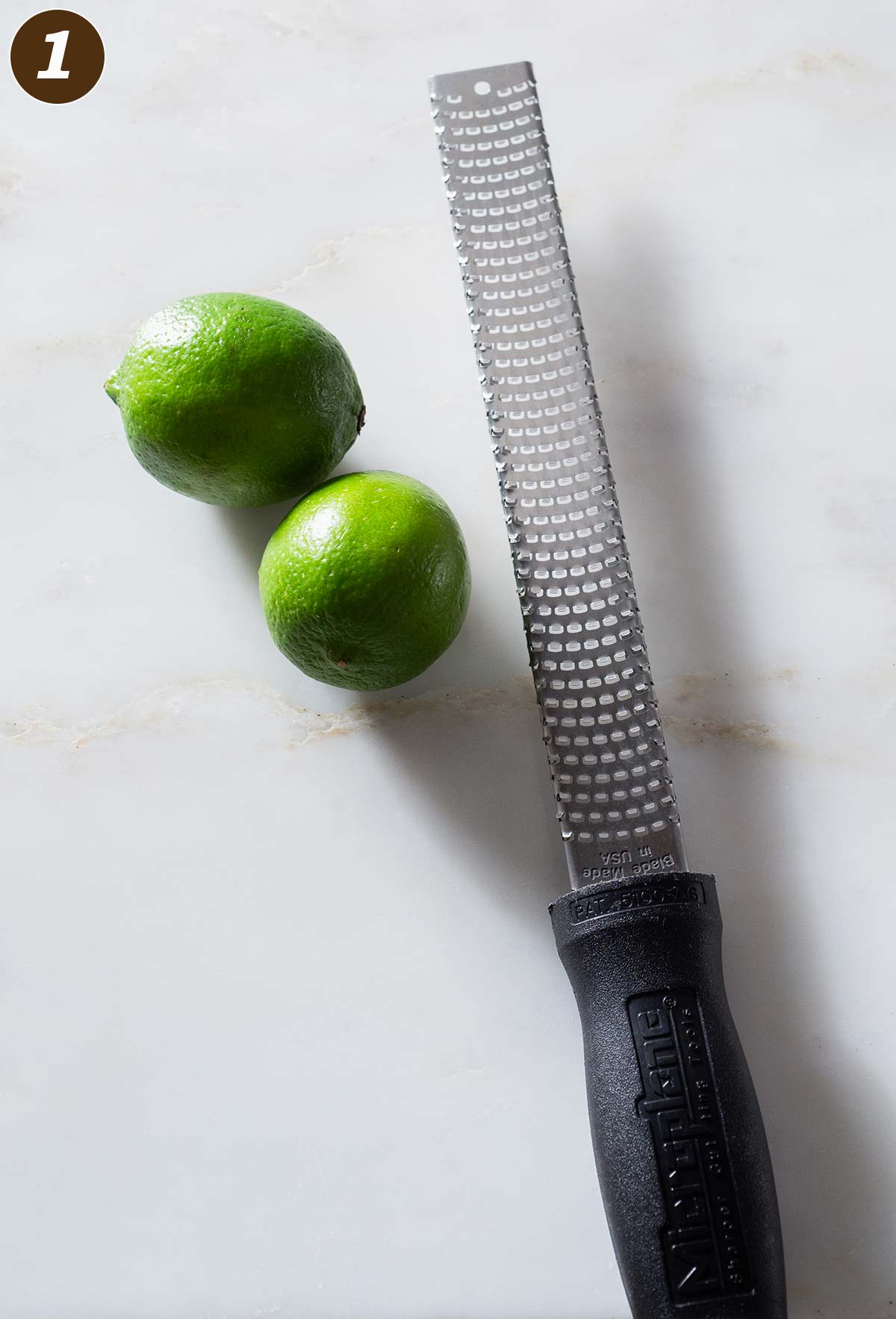 Limes and a zester on a table.