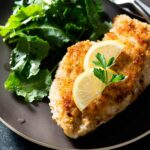 Fried breaded lemon panko chicken breast with salad on a plate.