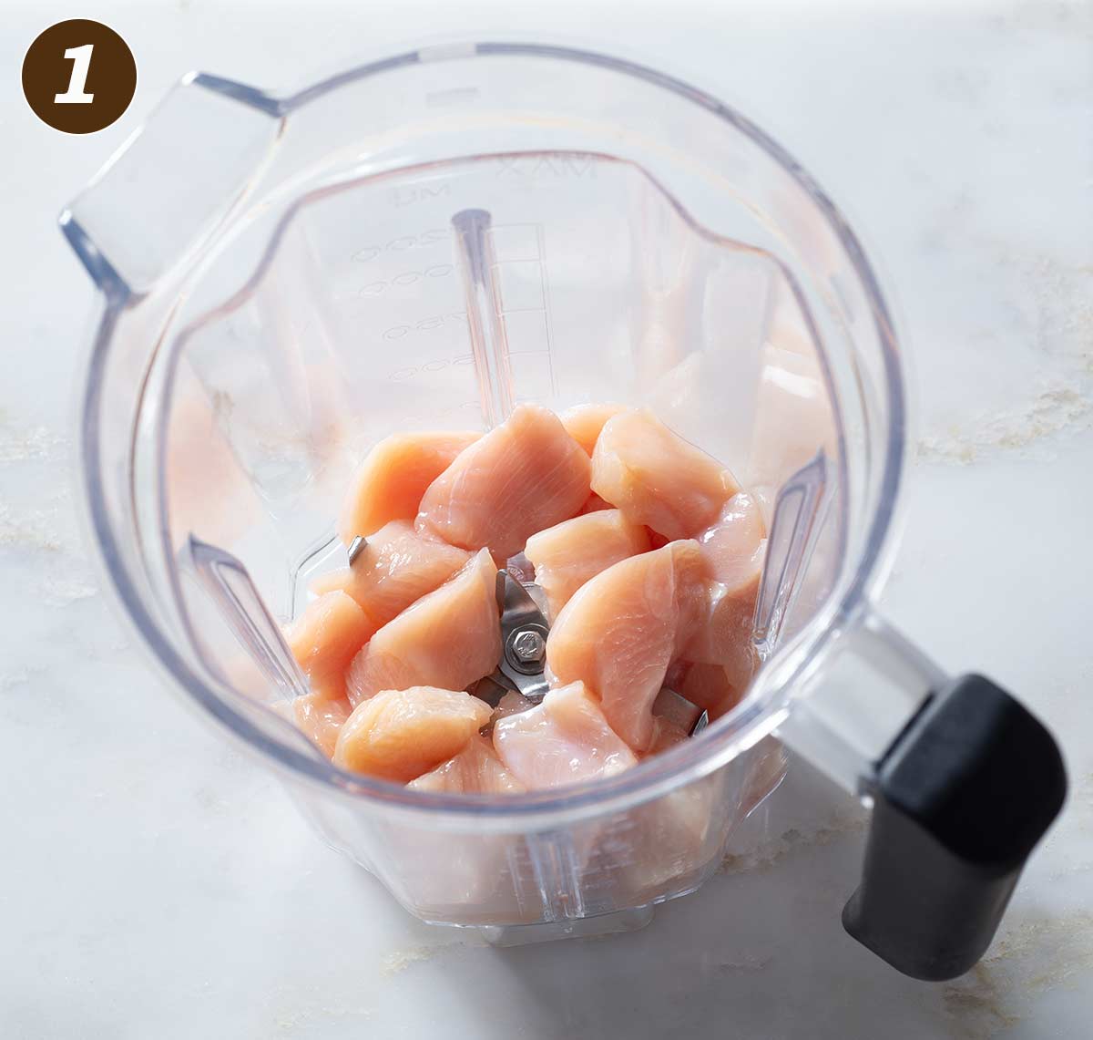 Raw chicken breast chunks in a blender.