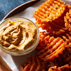 Sweet potato fries on a plate with chili aioli in a bowl.
