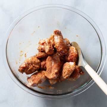 Chicken wings being tossed in a bowl.