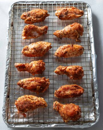 Seasoned chicken wings on a wire rack.