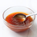 Apricot dipping sauce in a bowl with a spoon.