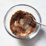Mexican chicken seasoning being mixed in a glass bowl.