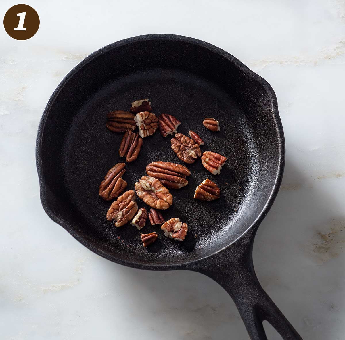Toasted pecans in a small cast iron pan.