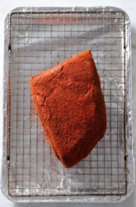 Spice-rubbed pork butt on a baking sheet.