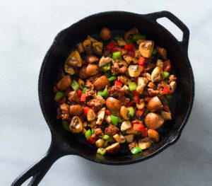 Browned chicken, chorizo and vegetables in a cast iron pan.