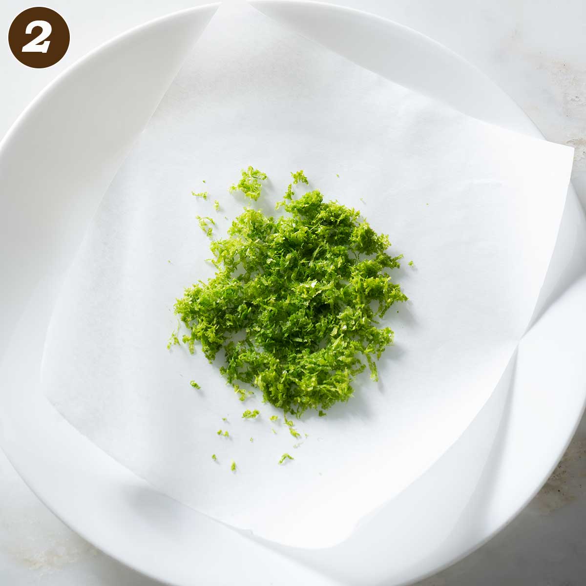 Lime zest on wax paper on a plate.