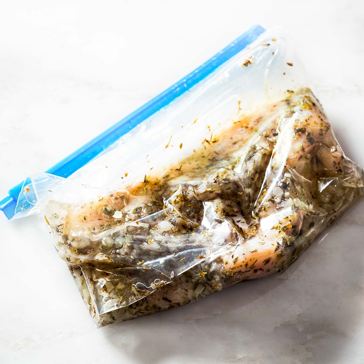 Chicken with marinade in a resealable plastic bag.