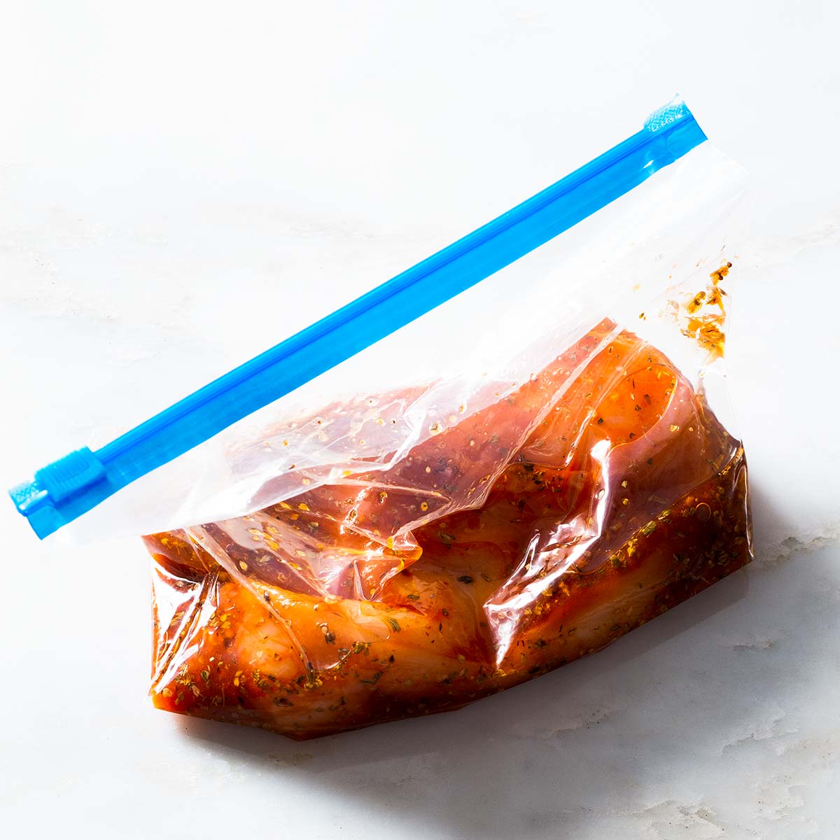 Raw chicken with honey chili marinade in a plastic bag.