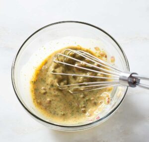 Dill honey mustard sauce being whisked in a bowl.